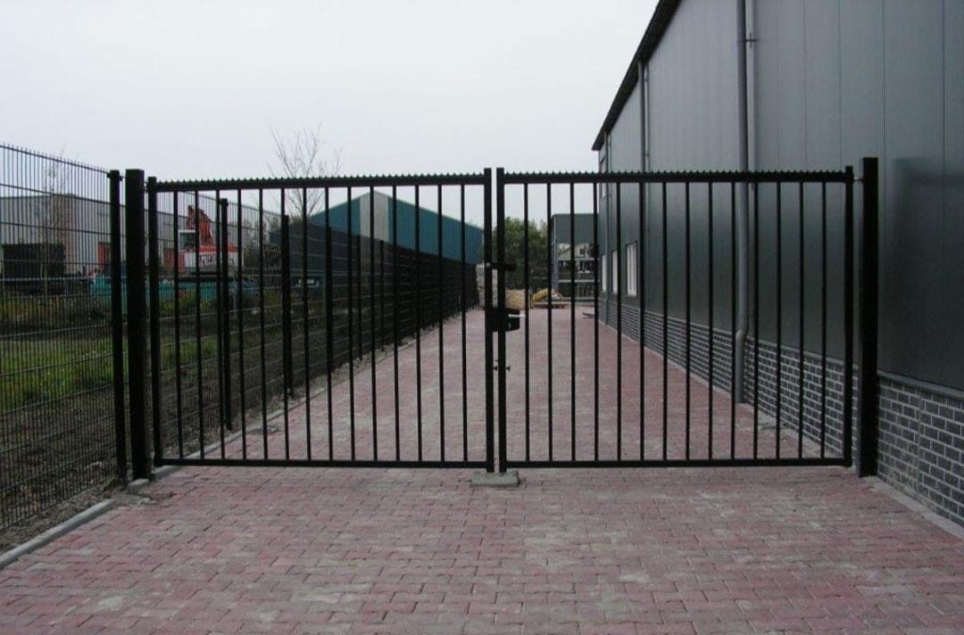 Black vertical-bar double gates at a commercial yard